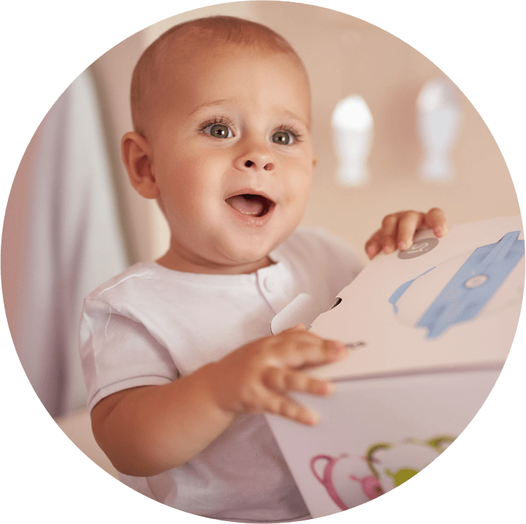 Un petit garçon fasciné tenant la boîte du mouche-bébé électrique Nosiboo Pro