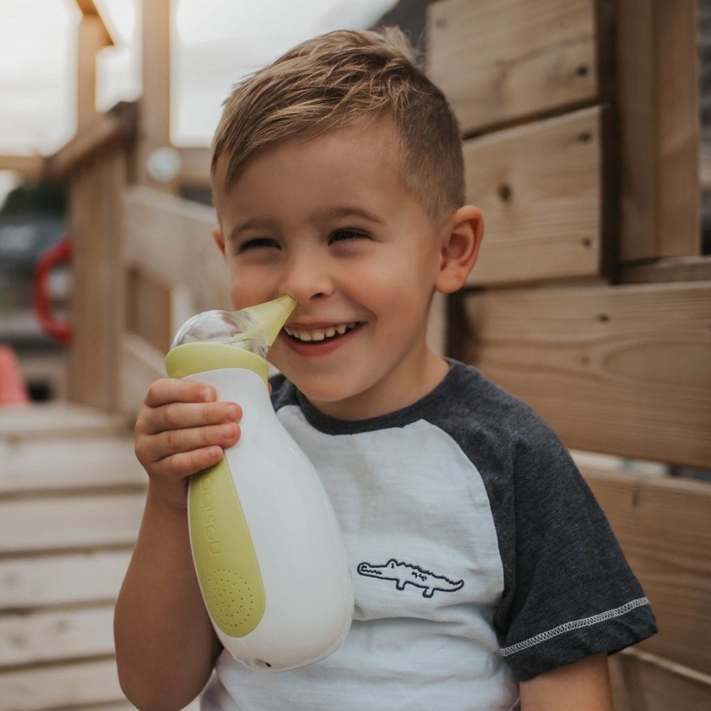 Petit garçon souriant tenant un mouche-bébé électrique Nosiboo Pro