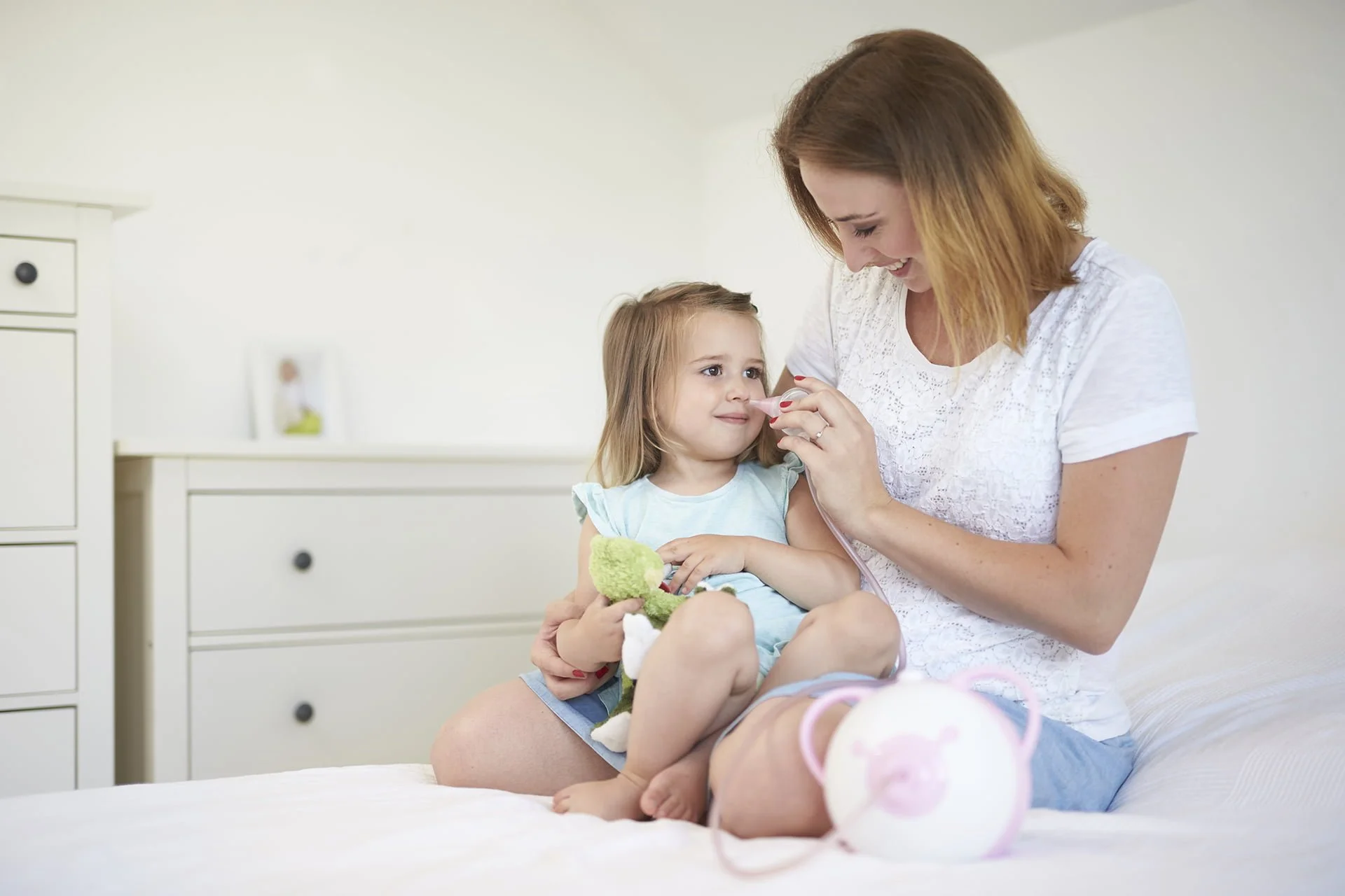 Afficher une photo en taille réelle d'une mère qui dégage le nez de sa petite fille à l'aide d'un mouche-bébé électrique Nosiboo Pro