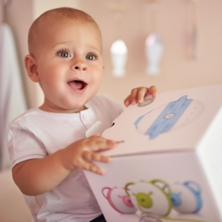 Un petit garçon fasciné tenant la boîte du mouche-bébé électrique Nosiboo Pro