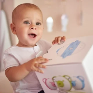 Un petit garçon fasciné tenant la boîte du mouche-bébé électrique Nosiboo Pro