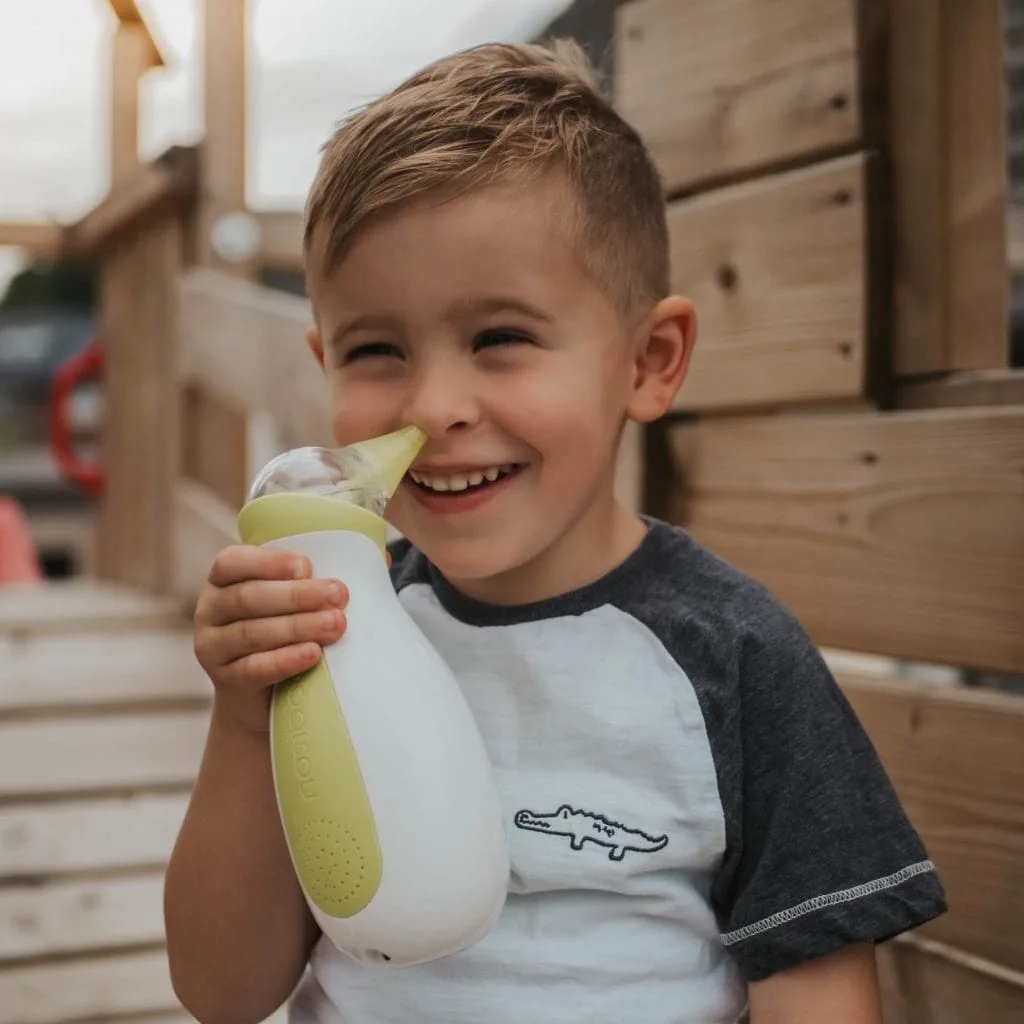Petit garçon souriant tenant un mouche-bébé électrique Nosiboo Pro