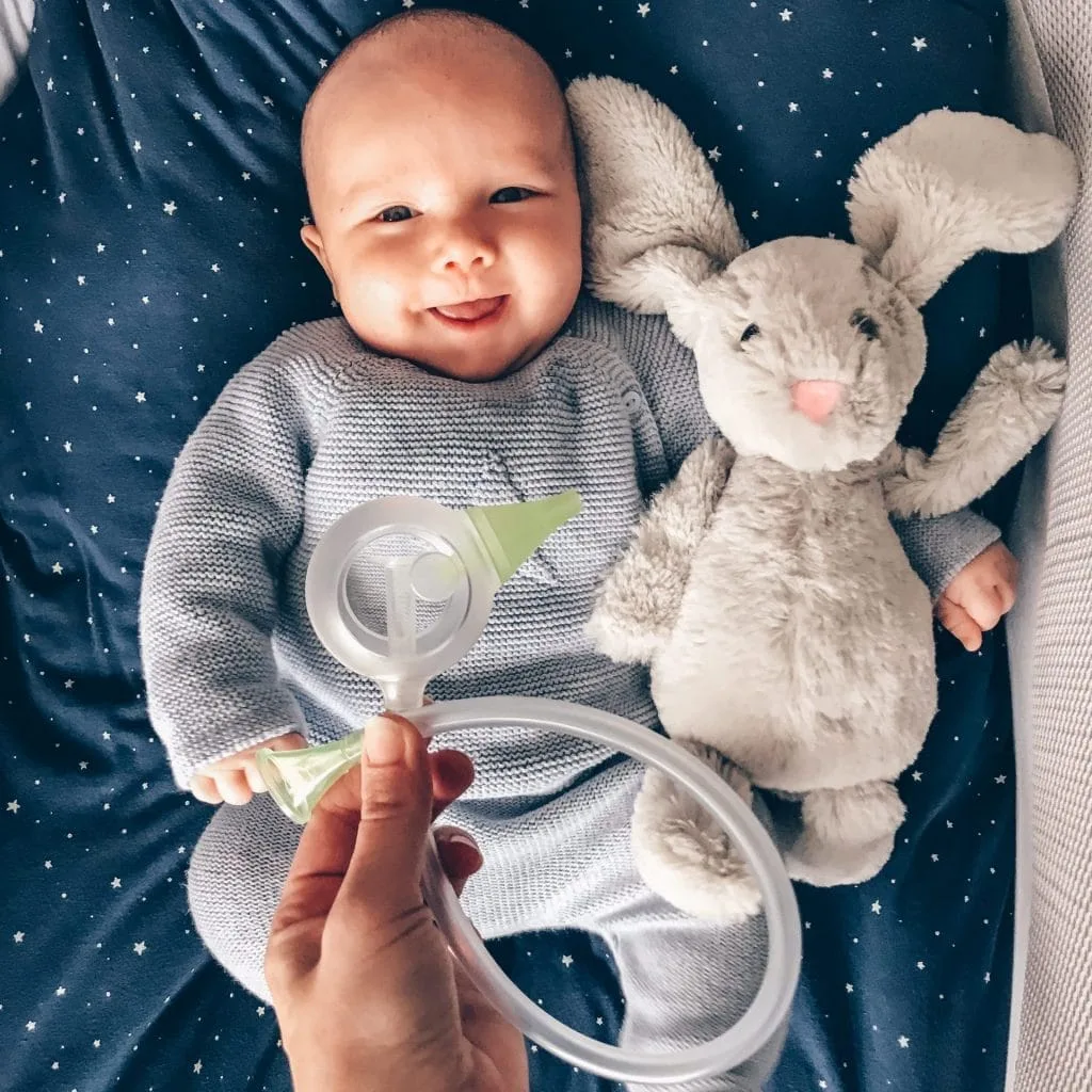 Quelqu'un tient un mouche-bébé manuel Nosiboo Eco au-dessus d'un bébé souriant