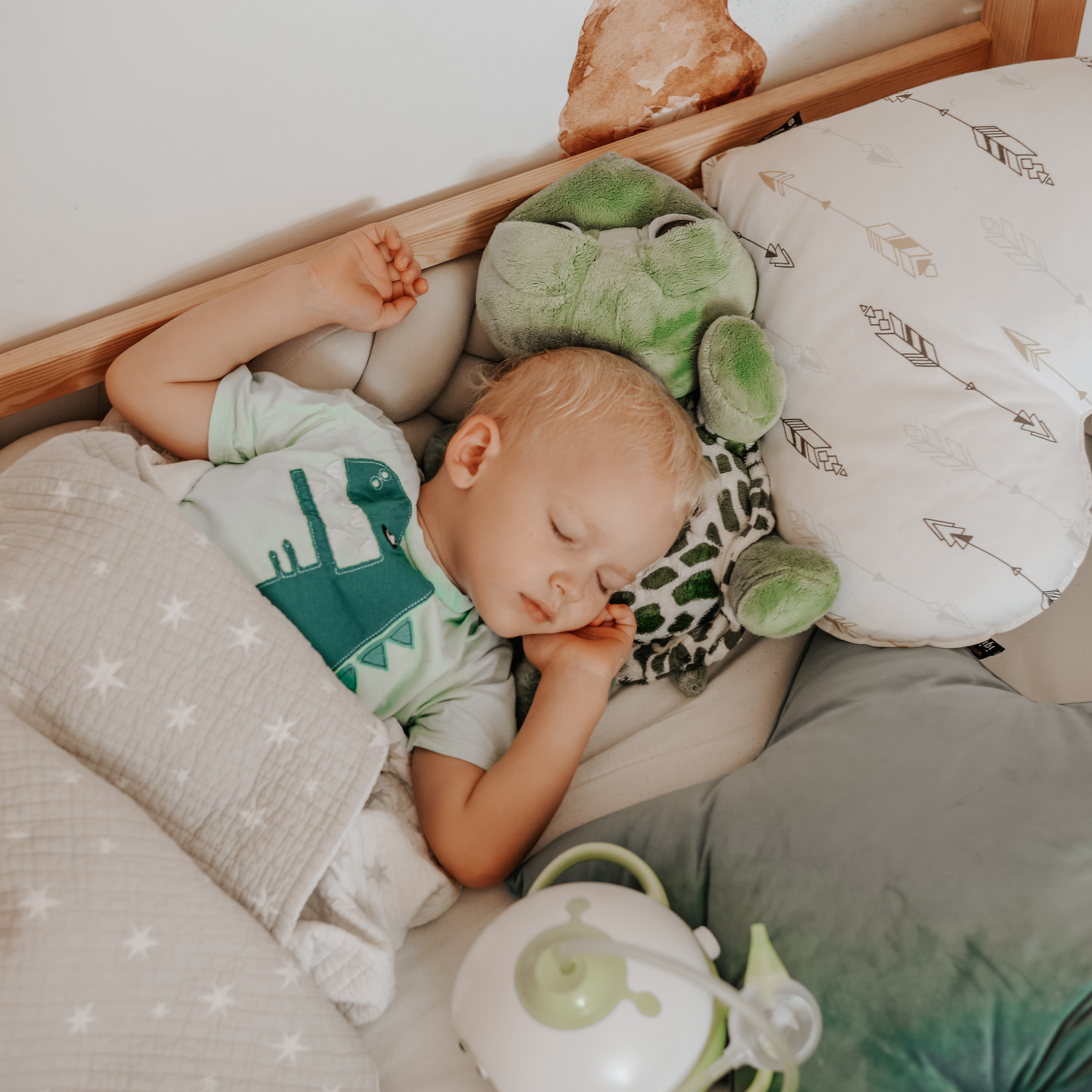 Little boy sleeping sound in his bed next to a green Nosiboo Pro electric nasal aspirator