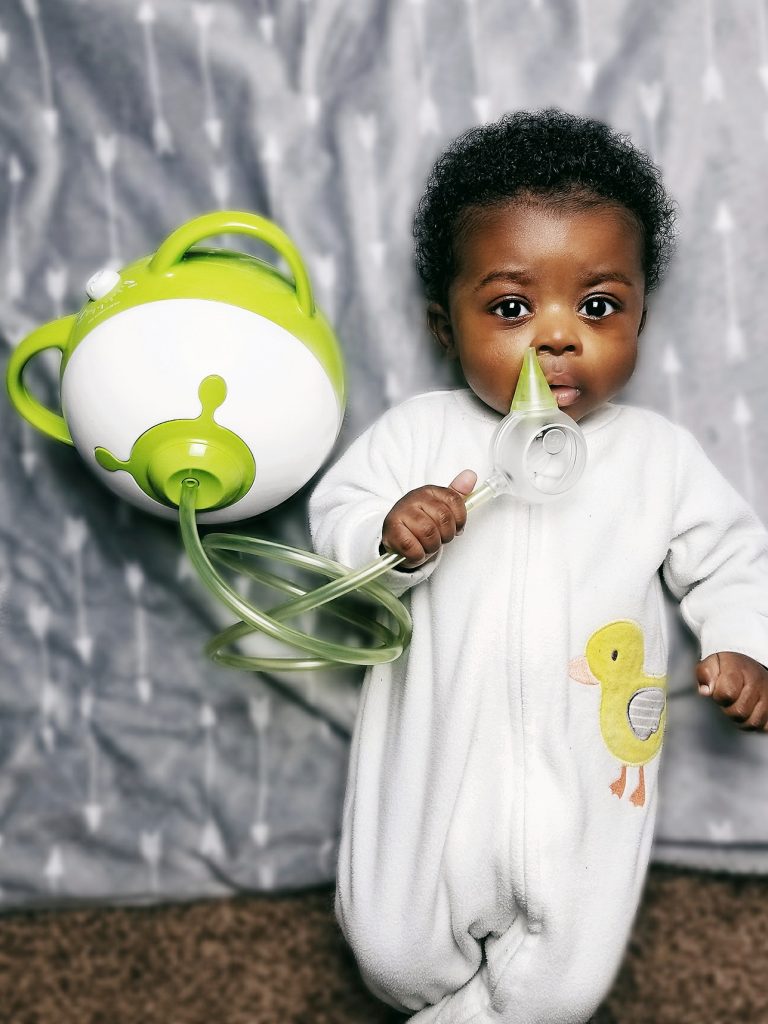 Un petit garçon jouant avec un mouche-bébé électrique Nosiboo Pro vert