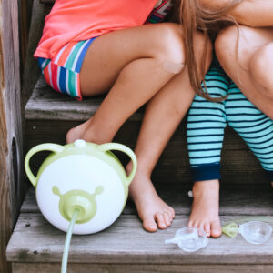 Un mouche-bébé électrique Nosiboo Pro avec une tête Colibri démontée sur l'escalier à côté de deux petites filles.