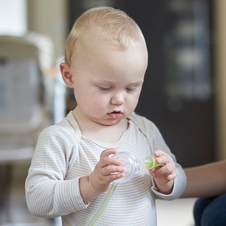 Un petit garçon jouant avec un mouche-bébé électrique Nosiboo Pro