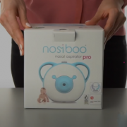 Une femme tenant la boîte du mouche-bébé électrique Nosiboo Pro.