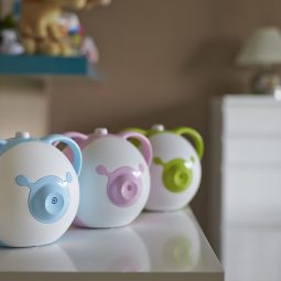 Afficher une photo en taille réelle du mouche-bébé électrique Nosiboo Pro en trois couleurs sur une étagère dans la chambre d'enfant